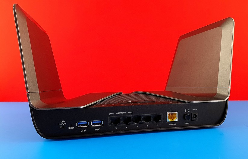 Schnittstellen des Netgear RAX80 Multi-Gigabit-WLAN-AX-Funkers, von Links: LED-Ein-Aus-Schalter, Reset-Taster-Loch, 2x USB30, 5x 1000-MBit/s-LAN, 1x 1000-MBit/s-Internet-WAN, Strom-Ein-Aus-Schalter, DC-IN-Stromzufuhr (Bild: Harald Karcher).