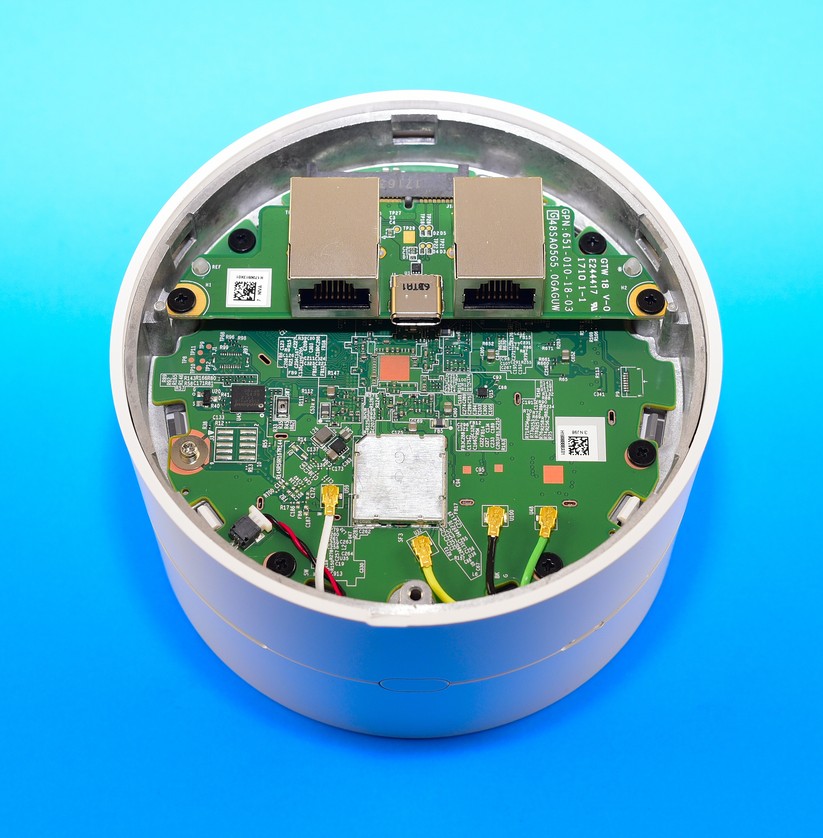 Wir haben den Boden eines Google Wifi Mesh Points abgeschraubt. Oben im Bild sitzen zwei silberne Kästchen: Das sind die LAN-WAN-Kabel-Buchsen. Unten im Bild auf der grünen Hauptplatine vier kleine, goldene Stecker: Die Kabel (weiß, gelb, schwarz, grün) führen zu den WLAN-Antennen im Kopf des Mesh-Points (Bild: Harald Karcher).
