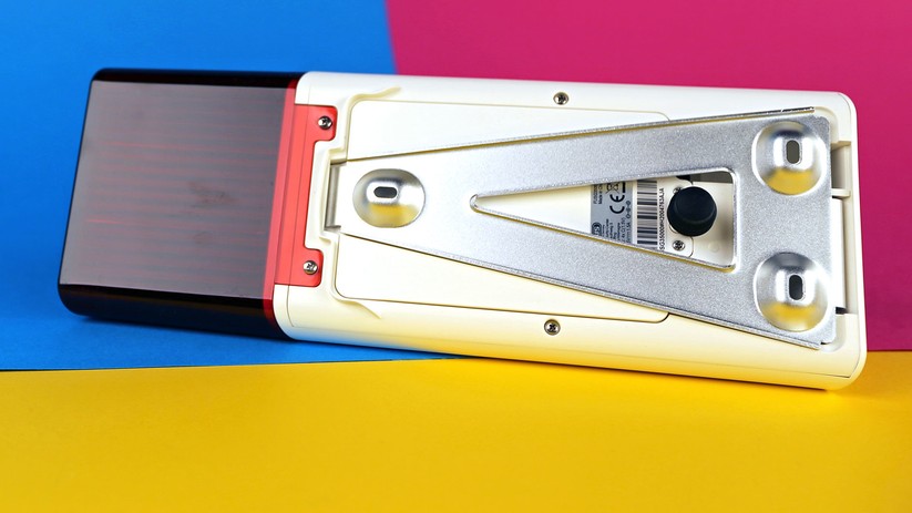 Bei der Alarmsirene ist ein Alurahmen zur Wandmontage angebracht. Der schwarze Gumminippel ist ein gefederter Schalter – er bemerkt, wenn die Schraube gelöst oder die Sirene von der Wand gerissen wird.