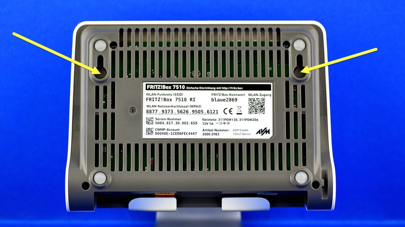 Tatsächlich hat die Fritzbox zwei passende Ösen für die Wandaufhängung. Schrauben und Dübel werden allerdings nicht mitgeliefert. Dafür gibt es im großen PDF-Handbuch auf Seite 254 aber eine Bohrschablone, die man selber ausdrucken kann.