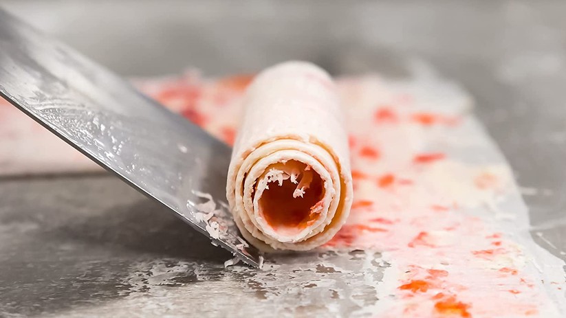 Das schnell anfrierende Eis rollt sich beim Abschaben von der tiefgekühlten Unterlage.