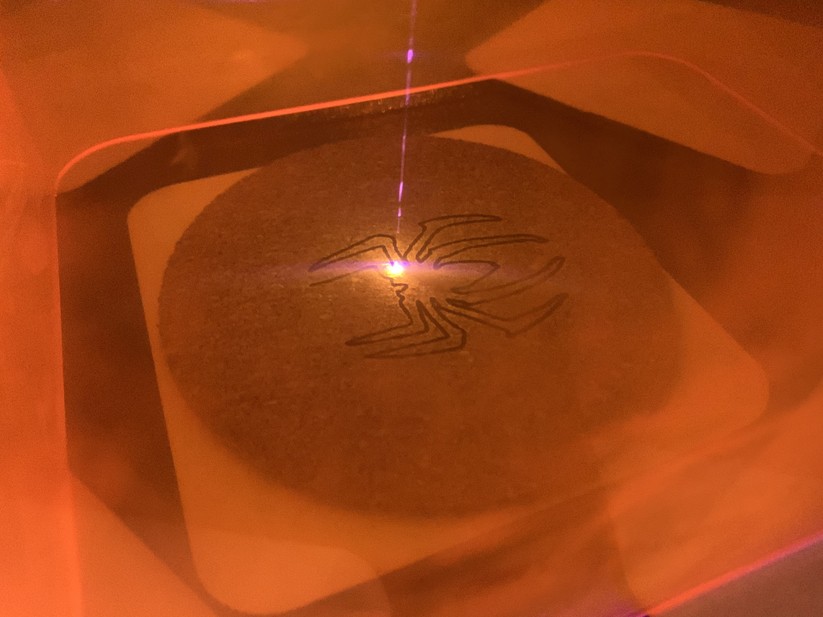 Das Laser Pecker bei der Arbeit: Hier graviert er gerade eine Spinne in einen Glasuntersetzer aus Kork.