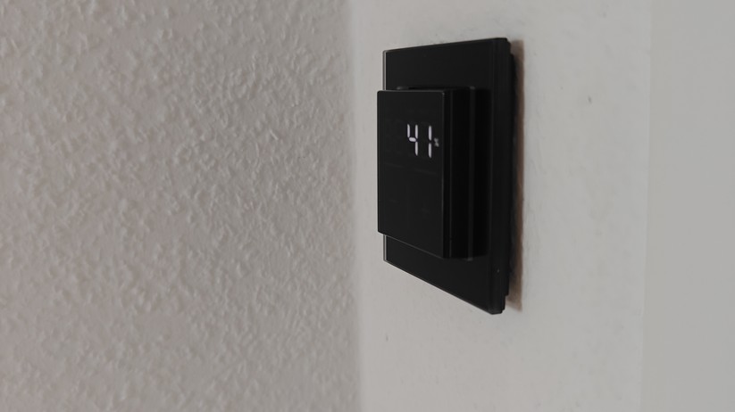 Das Homematic IP Glas-Wandthermostat mit CO₂-Sensor gibt es in Schwarz oder Weiß. Auf seinem Glas-Display kann es Temperatur, Luftfeuchte und CO₂-Konzentration abwechselnd anzeigen.