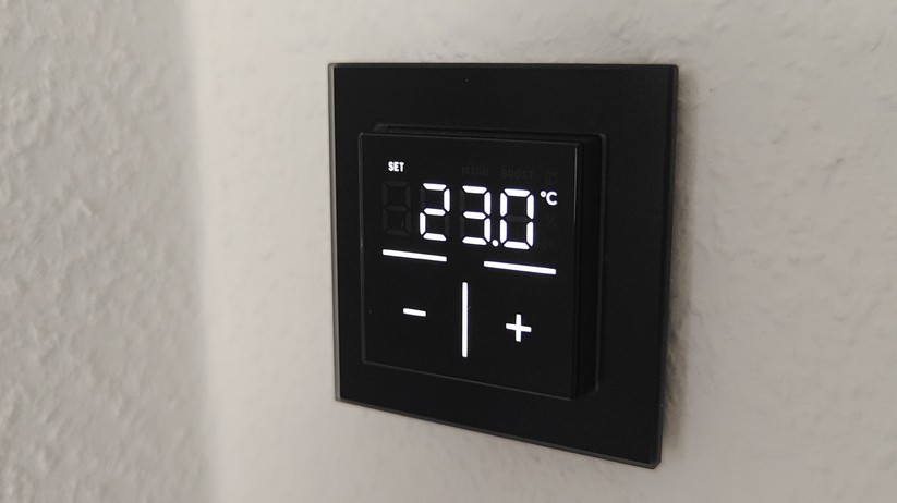 Das Homematic IP Glas-Wandthermostat mit CO₂-Sensor gibt es in Schwarz oder Weiß. Auf seinem Glas-Display kann es Temperatur, Luftfeuchte und CO₂-Konzentration abwechselnd anzeigen.