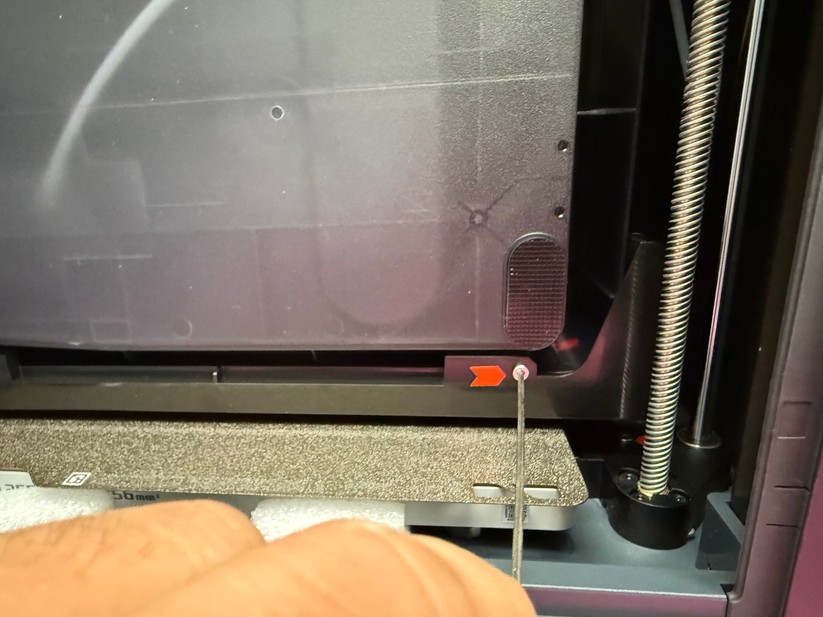 Die zu entfernenden Schrauben der Transportsicherung sind in der gedruckten Anleitung ersichtlich und mit roten Pfeilen markiert. 