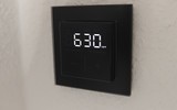 Das Homematic IP Glas-Wandthermostat mit CO₂-Sensor gibt es in Schwarz oder Weiß. Auf seinem Glas-Display kann es Temperatur, Luftfeuchte und CO₂-Konzentration abwechselnd anzeigen.