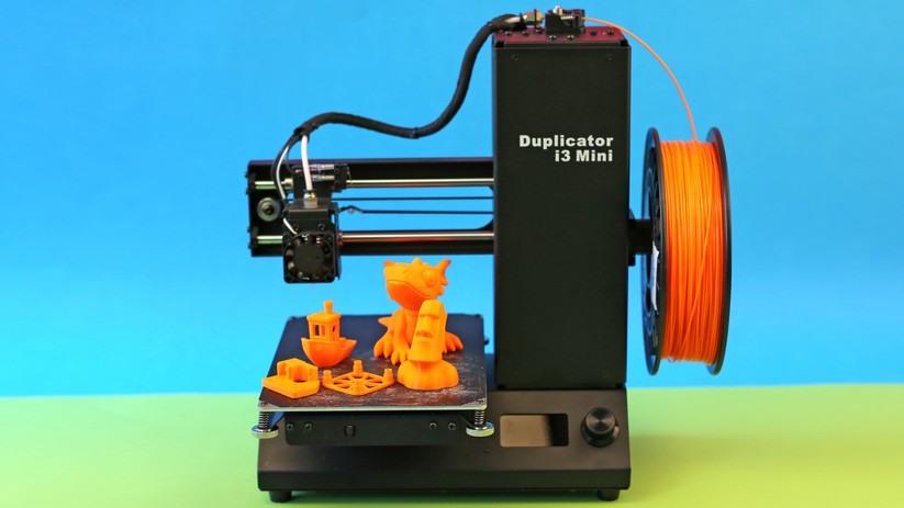 Standardmäßig arbeiten 3D-Drucker nur einfarbig: Das Verbauchsmaterial (Rolle im Bild rechts) gibt die Farbe der Objekte vor.