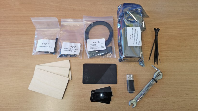 Neben Kabeln, Werkzeug, Card Reader, Speicherkarte  und Kabelbindern gehört auch Mustermaterial und eine Abstandsplatte zur Fokussierung zum Lieferumfang. 